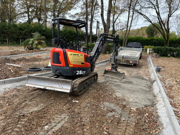Mini-pelle en action lors de travaux VRD, nivellement du terrain pour la création d’une voirie et la mise en place des réseaux.