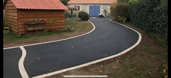Allée d’accès en enrobé bitumineux noir avec finition soignée en pavés clairs, réalisée par JÉROME TP pour un aménagement extérieur.