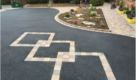 Allée en enrobé noir décorée d’un motif en pavés, réalisée par JÉROME TP pour un aménagement paysager soigné.
