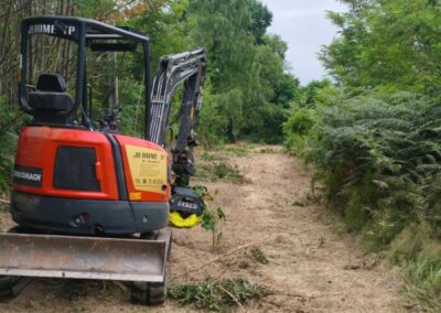 Débroussaillage de chemin d’accès avec mini-pelle équipée d’un broyeur forestier - JÉROME TP Mini-pelle JÉROME TP en intervention sur chantier de débroussaillage pour l’entretien et l’ouverture d’un chemin en zone boisée.