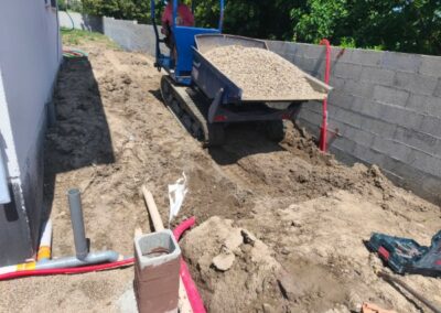 Remblaiement de tranchée avec gravier concassé sur chantier résidentiel - JÉROME TP Remblaiement d’une tranchée à l’aide d’un mini-dumper déversant du gravier sur un chantier de terrassement JÉROME TP.