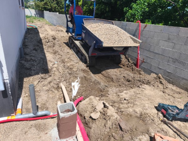 Remblaiement d’une tranchée à l’aide d’un mini-dumper déversant du gravier sur un chantier de terrassement JÉROME TP.