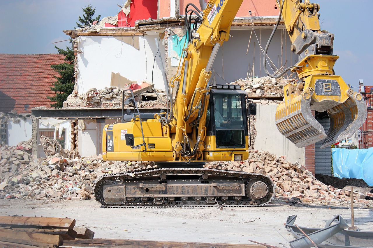 Engin de chantier en pleine démolition d’un bâtiment, utilisant un grappin pour tri et évacuation des gravats.